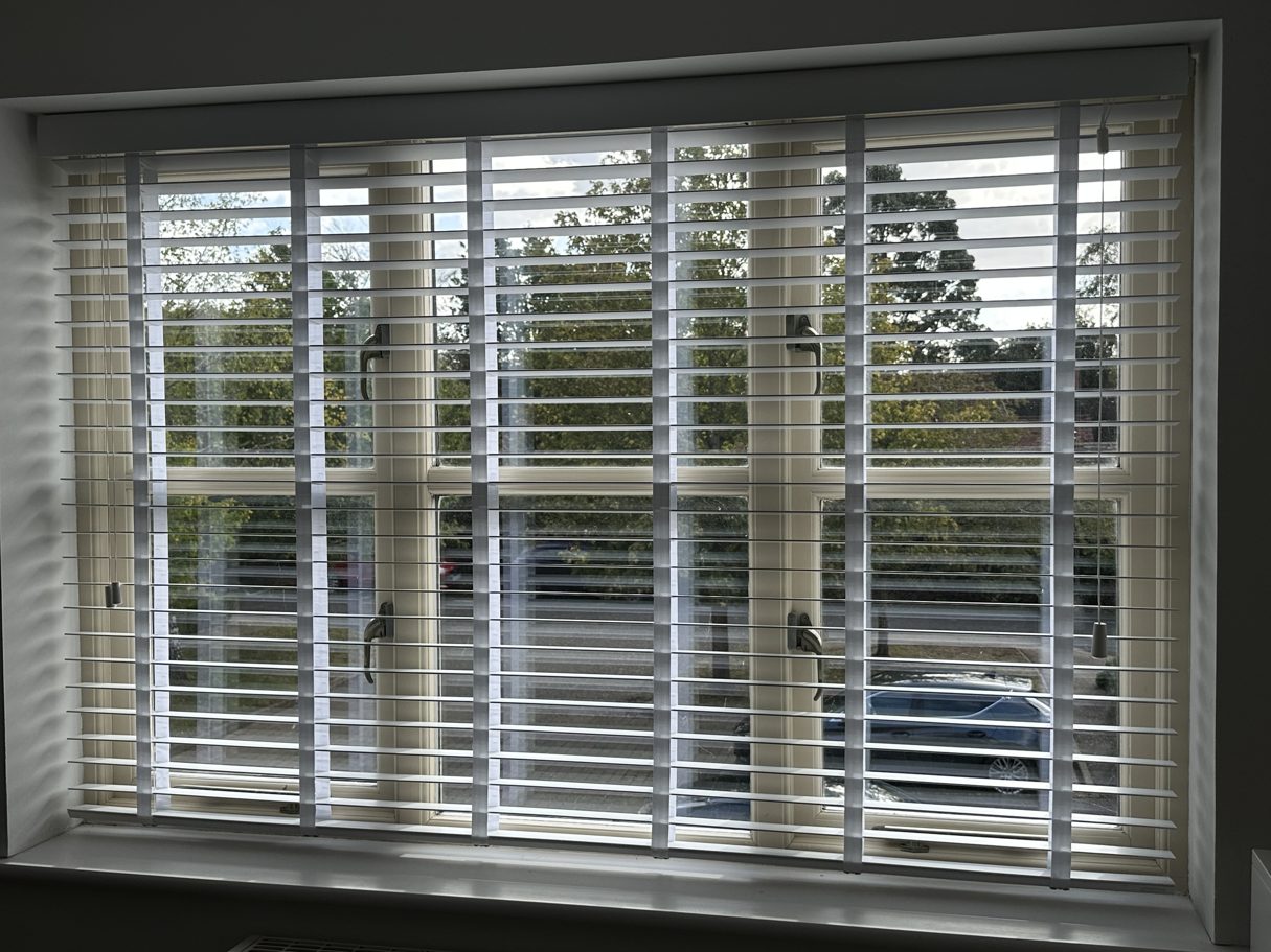 White wooden venetian blind fitted across a wide window