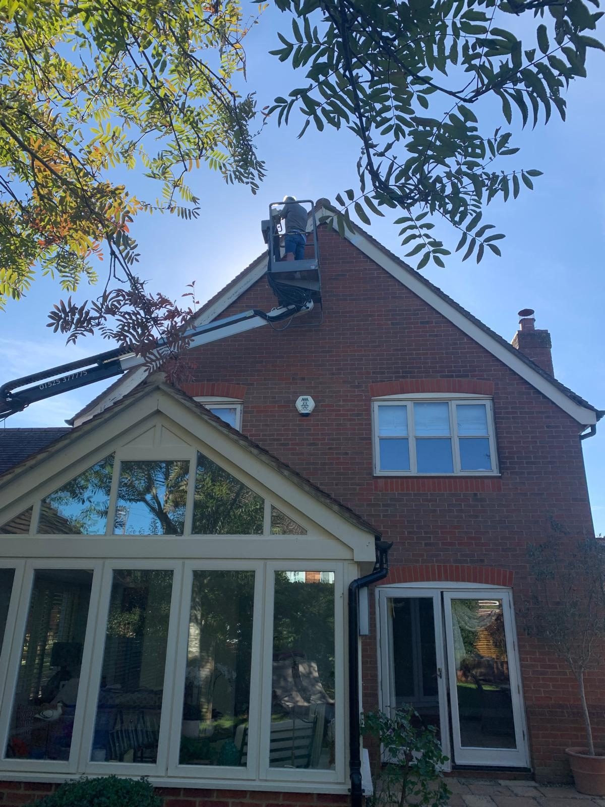 Working from a cherry picker on the gable fascias of a red brick house